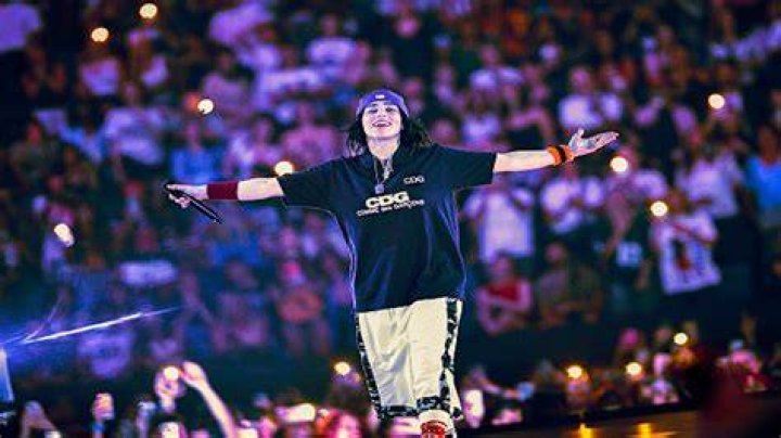 Billie Eilish, who says she has never smoked "weed," poses unsmiling with a sleep mask on her head at an event.
