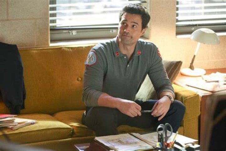 Brett Dalton at Jason Pelham in Chicago Fire Season 10. Pelham stands in front of a fire truck and looks concerned.
