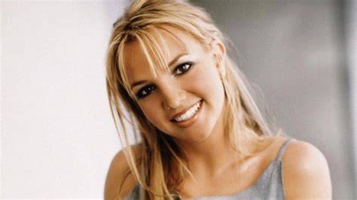 Britney Spears smiling and posing in a red dress/Columbus Short smiling in a tan vest and white shirt.