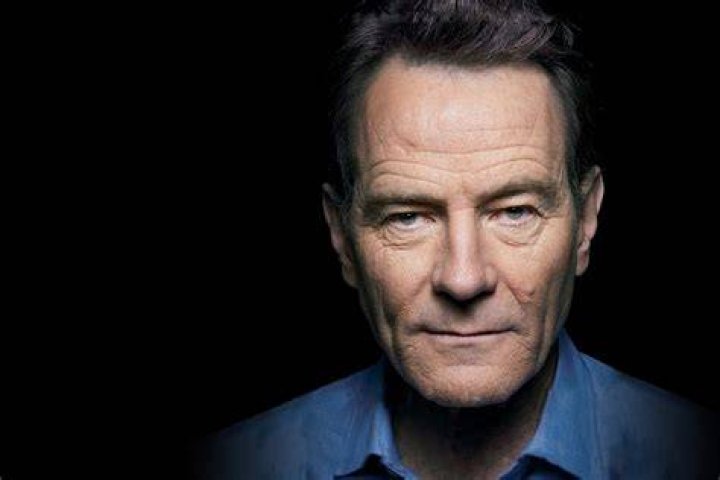 Bryan Cranston sitting next to Aaron Paul's bed