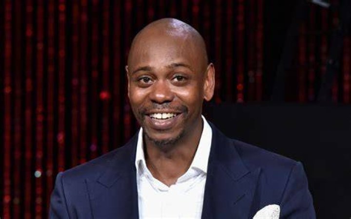 Dave Chappelle smiling in glasses.