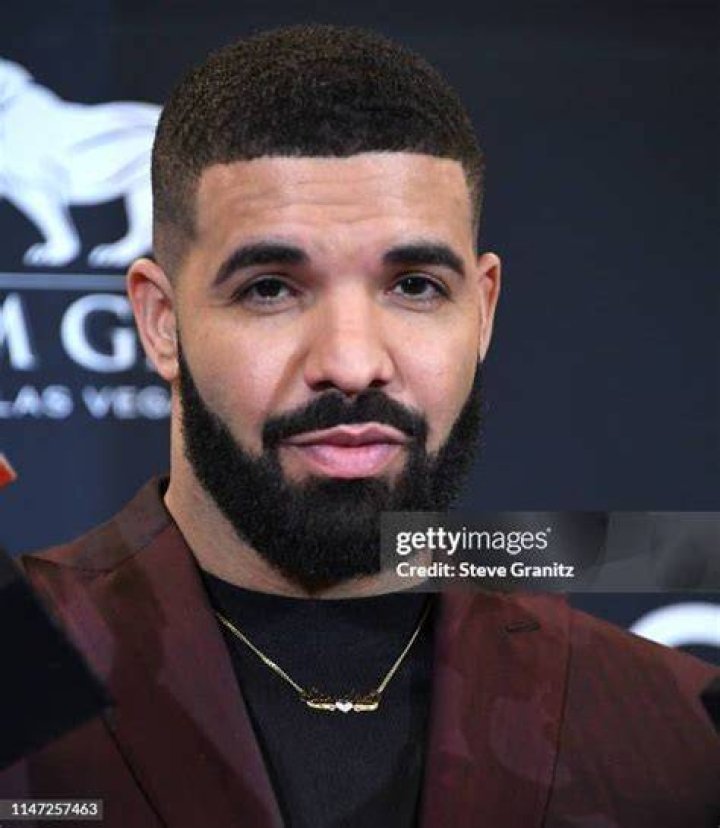 Drake poses with awards in a cream suit while smiling as winner of the Artist of the Decade Award, poses backstage for the 2021 Billboard Music Awards, broadcast on May 23, 2021 at Microsoft Theater in Los Angeles, California.