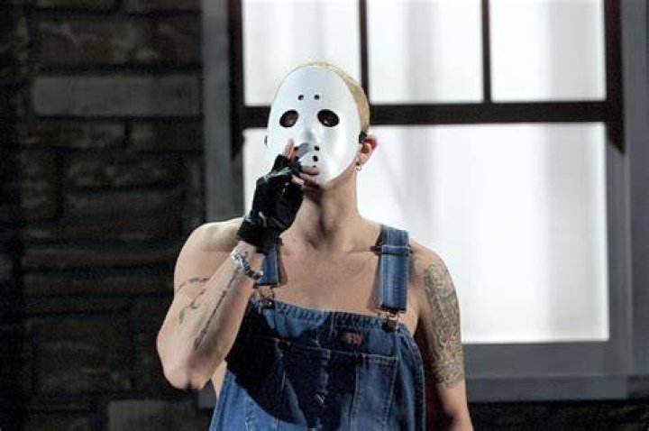 Eminem wearing a hockey mask holding a microphone.