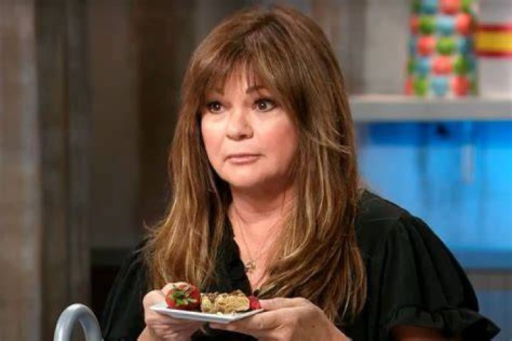 Food Network personality Valerie Bertinelli wears a black blouse as she prepares a dish.