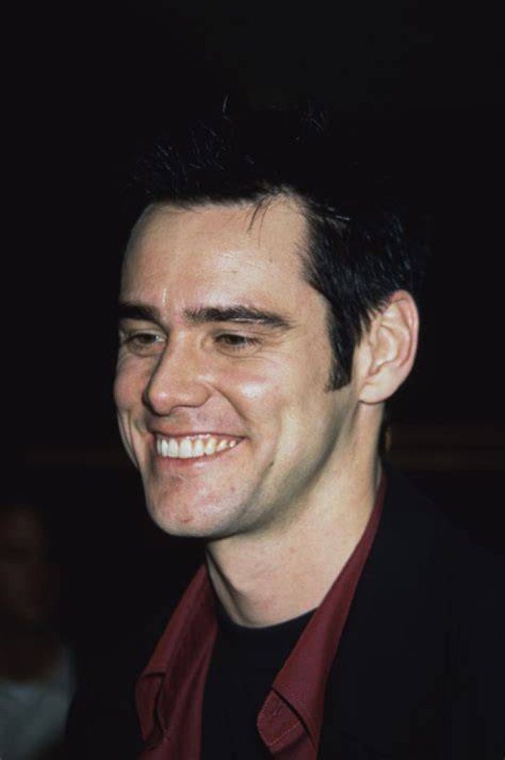 Jim Carrey smiling while wearing a red jacket.
