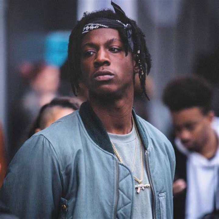 Joey Bada$$ as Unique smoking and looking at an object in 'Power Book III: Raising Kanan'