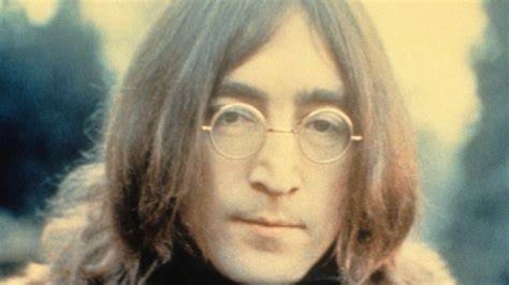 John Lennon holds a plate and sits next to The Rolling Stones' Mick Jagger.