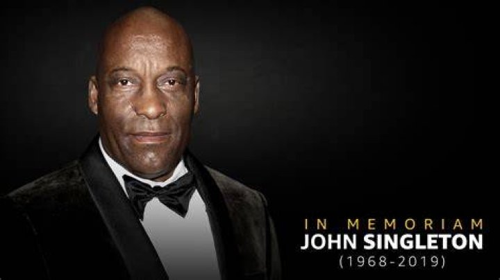 John Singleton, who planned to make a Tupac biopic, posing while wearing a buttoned white shirt.
