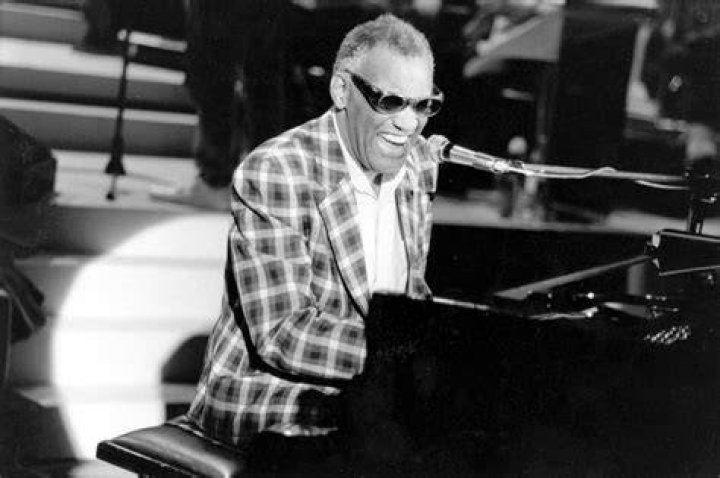 Ray Charles playing piano, singing into a microphone