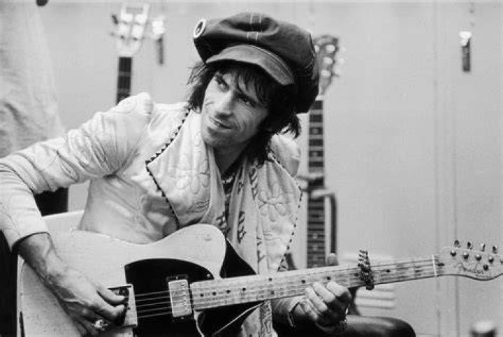 Rolling Stones guitarist Keith Richards wearing a black suit and headband during a 1988 solo performance.