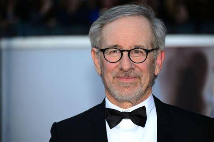 Steven Spielberg smiling in front of a blue background