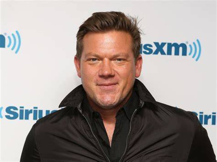 Tyler Florence wears a black shirt and gray apron as he cooks